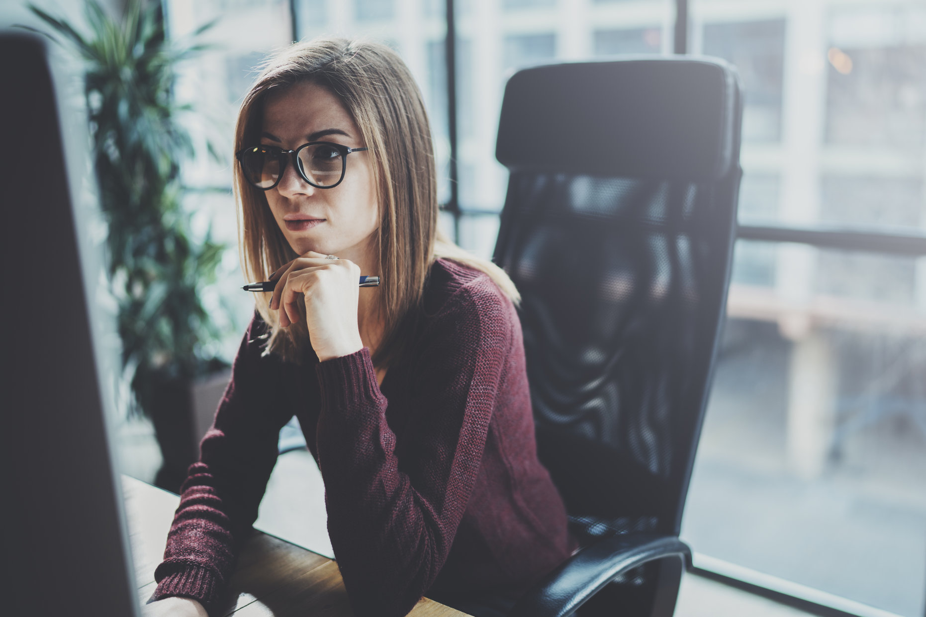 Attractive young businesswoman using desktop computer at modern working place at office.Blurred background.Horizontal.